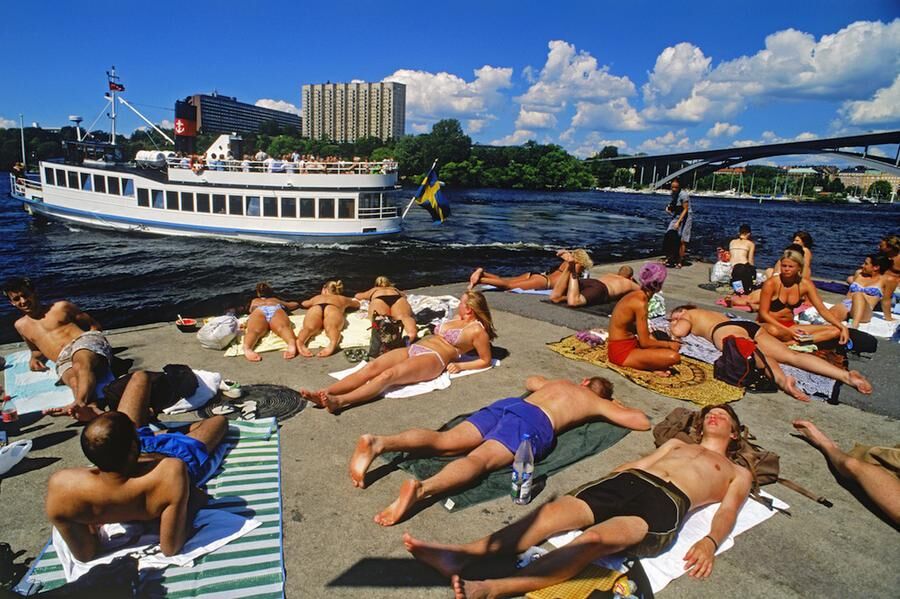 Sunbathers on cement pontoon at Langholmen Island in Stockholm with passing ferryboat on Riddarfjarden. Image shot 07/2006. Exact date unknown.