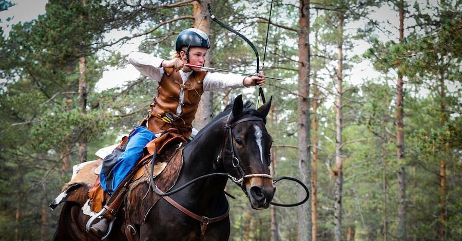 Eleven13-årige Marcus Hjortsberg från Tierp spränger fram på hästen medan han skjuter med pilbågen.