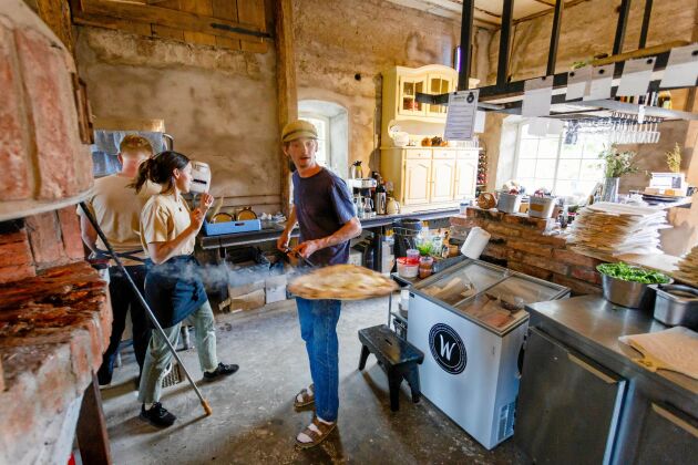  Filip med en rykande nygräddad pizza i köket som han, Sara och hans bror Arvid själva byggt i ladan.