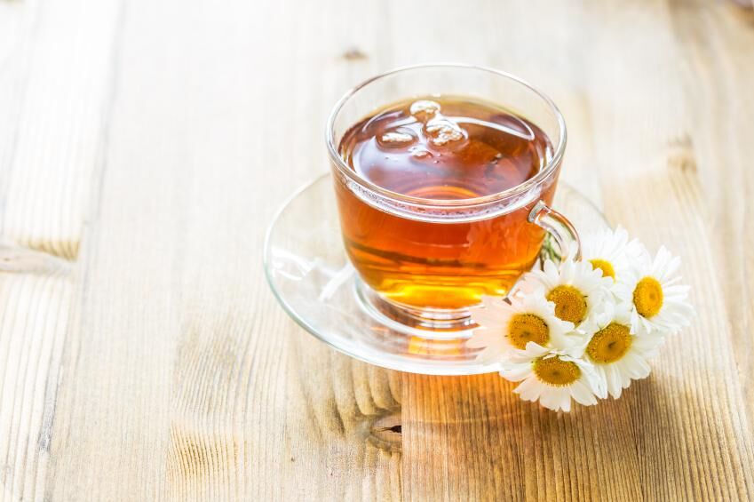 Cup of tea with chamomile flowers on rustic wooden background